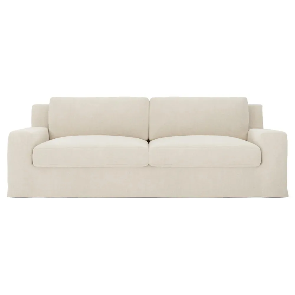 Slipcovered sofa in a warm chalk tone with a softly tailored skirt